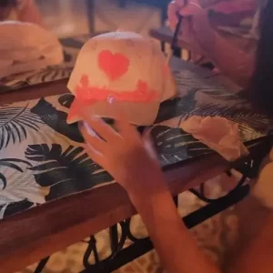 Crianças pintando bonés em oficina infantil